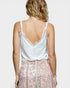 Woman wearing a white lace camisole and floral skirt on a plain background