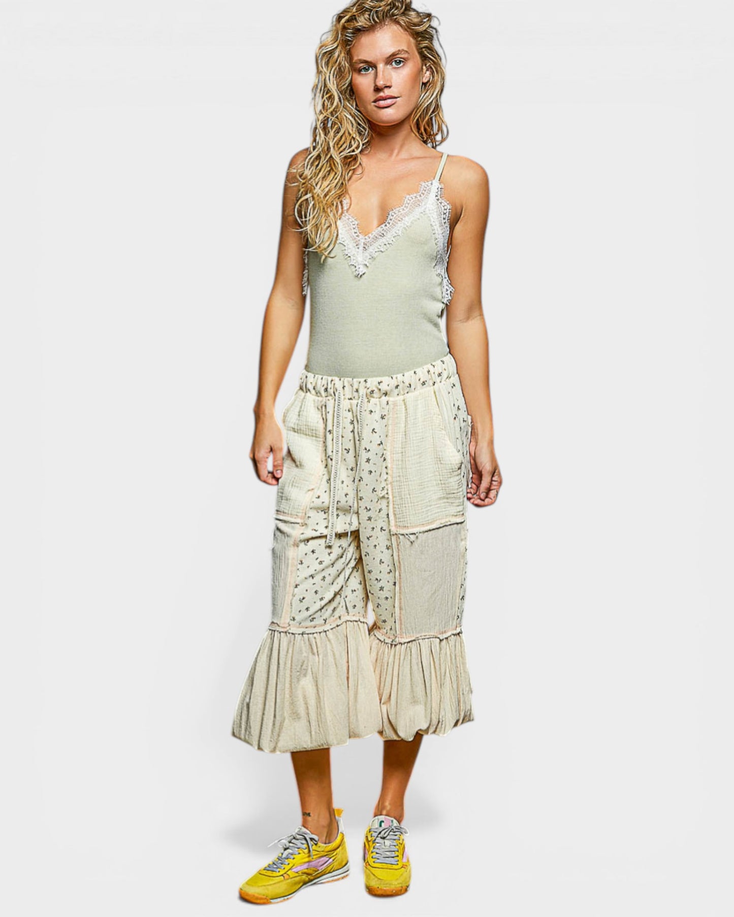 Woman wearing a light green top and beige skirt with floral patterns on a white background