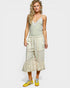 Woman wearing a light green top and beige skirt with floral patterns on a white background