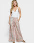 Woman wearing a white top and patterned pants on a white background