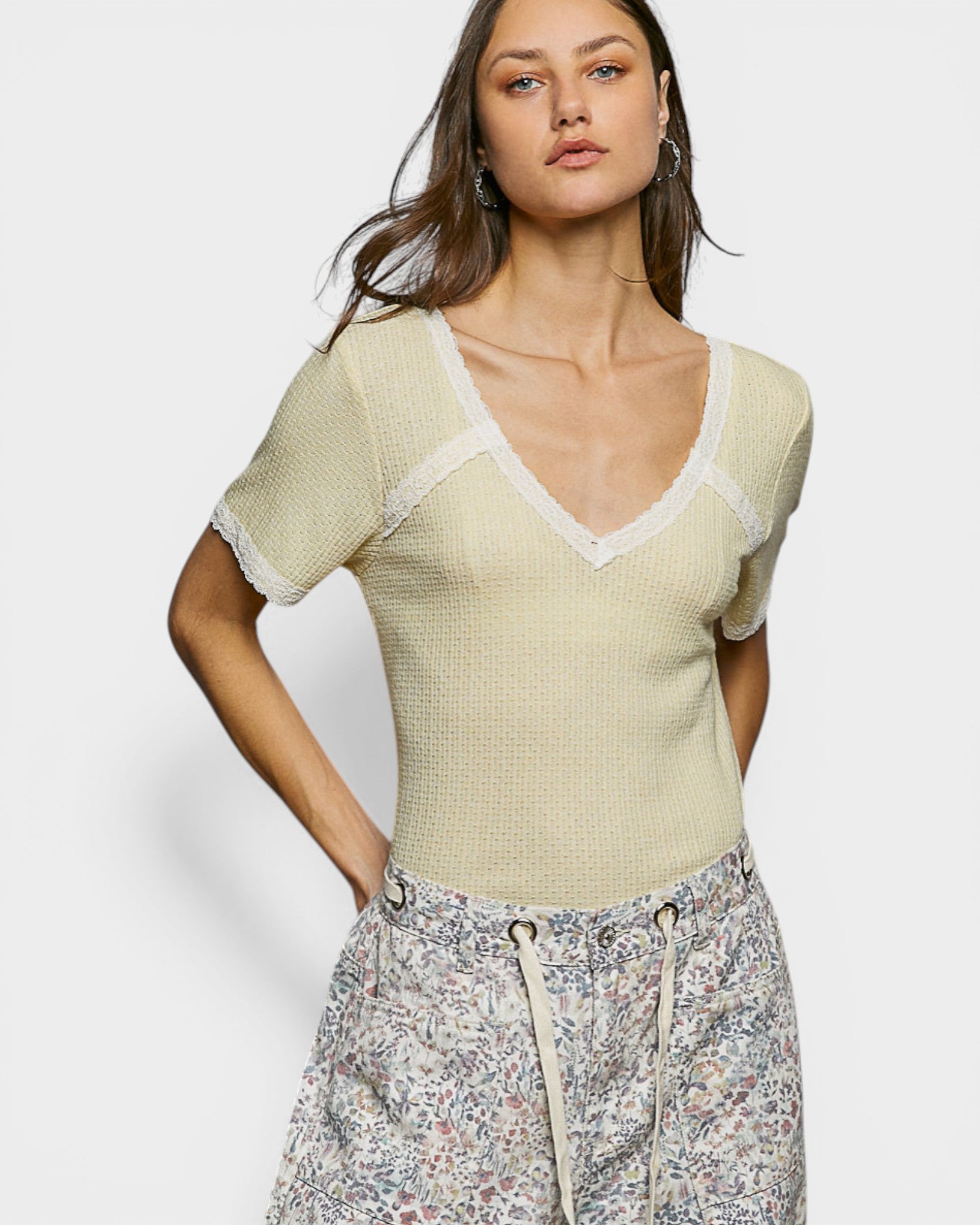 Woman wearing a light green knit top with a plain background