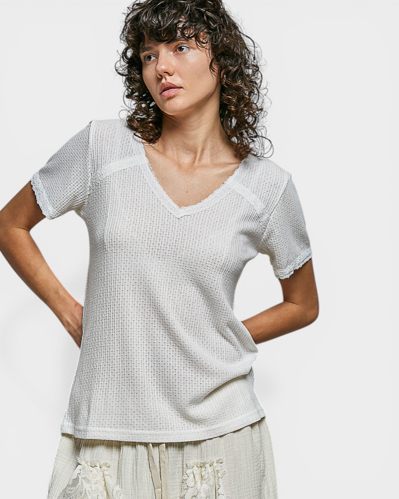 Woman wearing a textured white top against a plain background