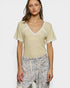 Woman wearing a light yellow top with floral pants on a white background