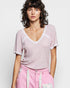 Woman wearing a light pink textured top and pink pants with white accents against a plain background