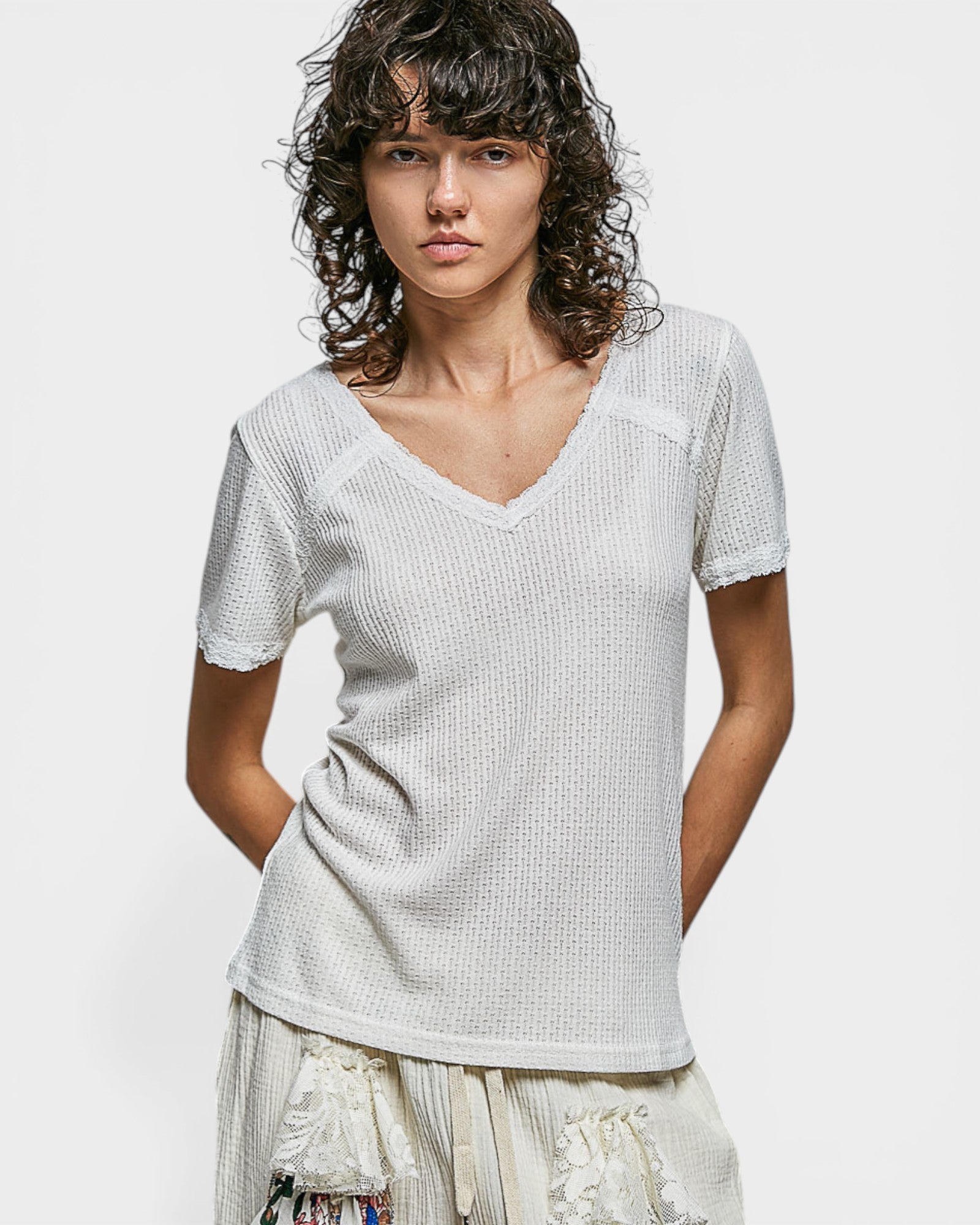 Woman wearing a textured white top against a plain background