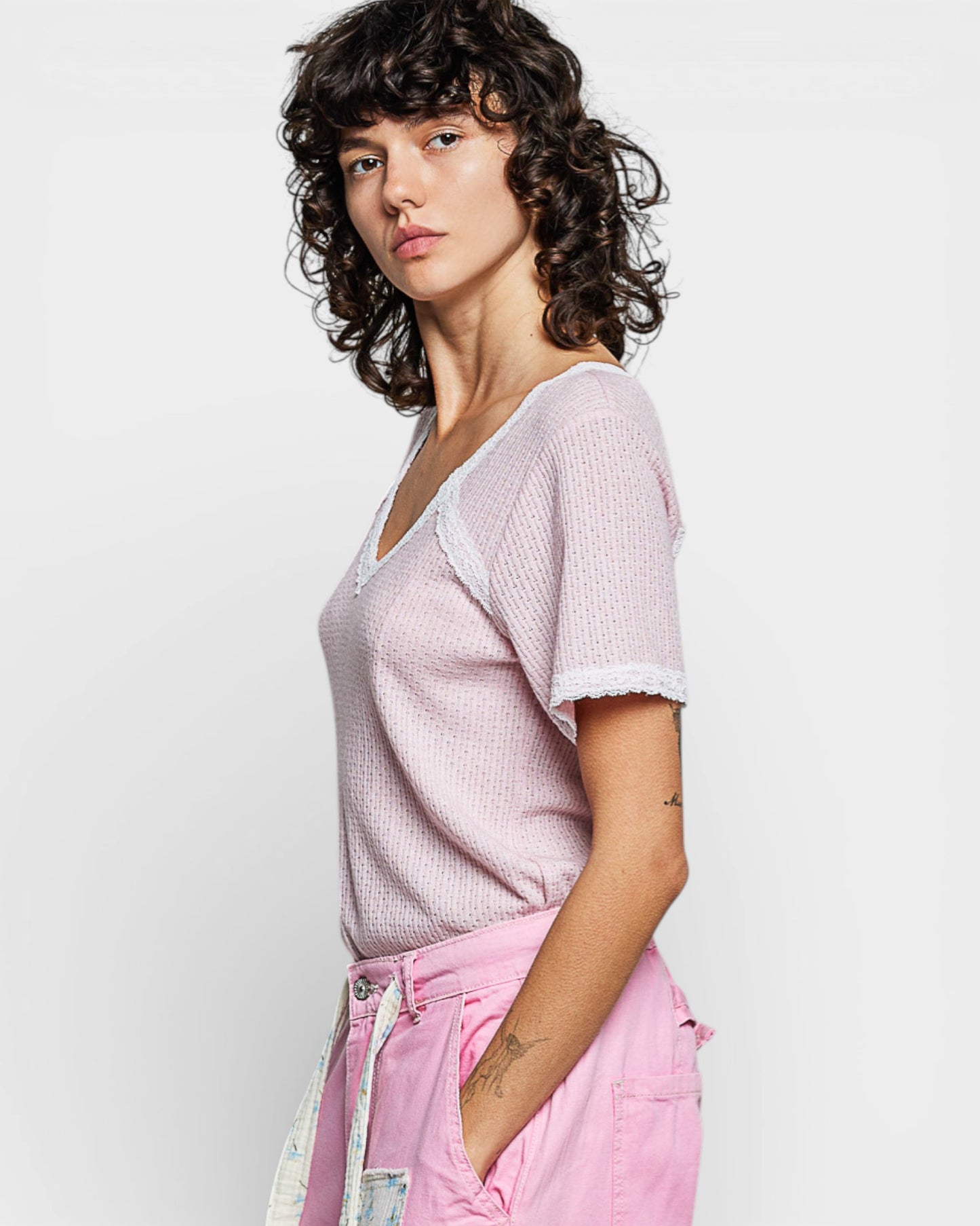 Woman wearing a light pink top and pink pants against a white background