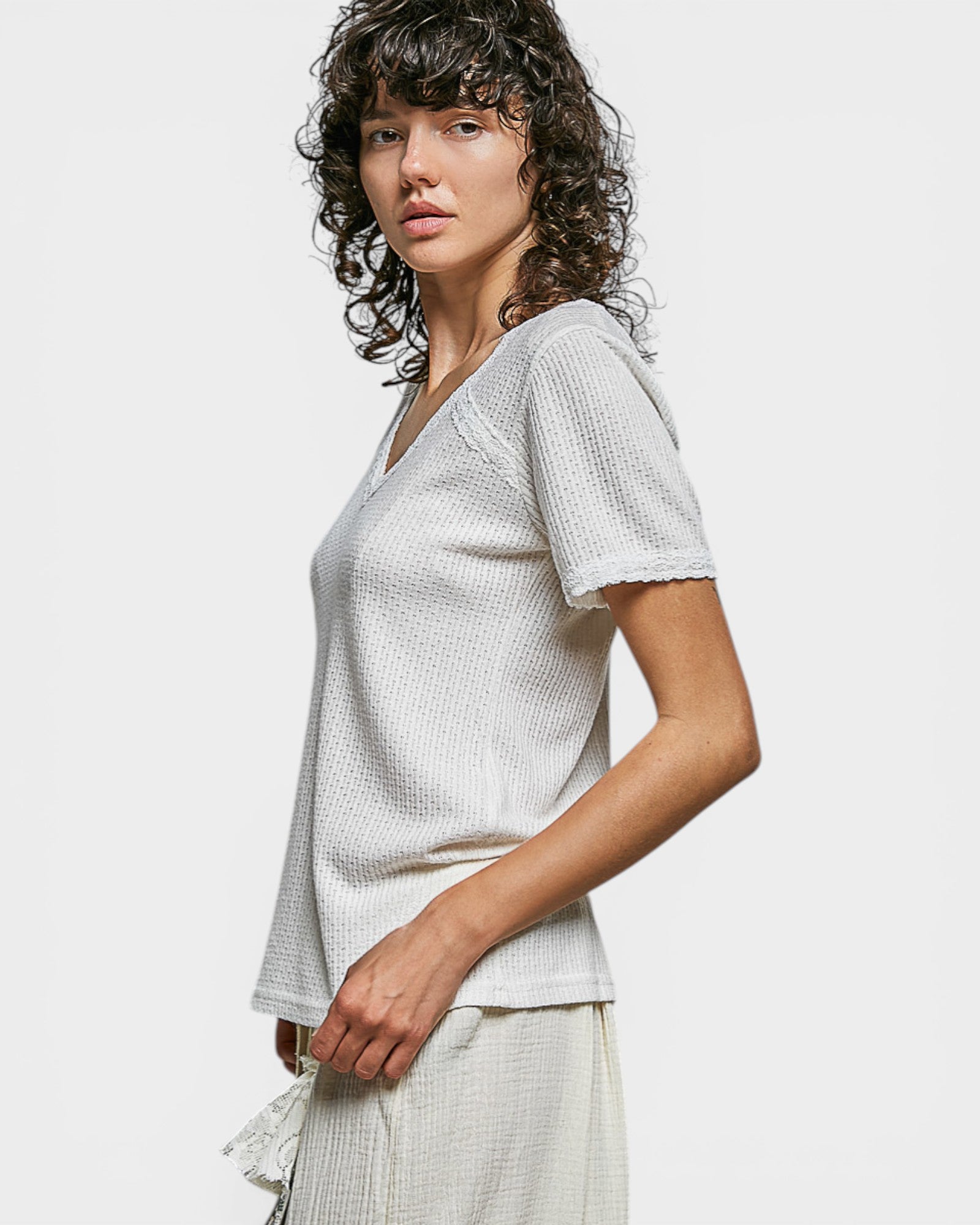 Woman wearing a light gray textured top against a plain background