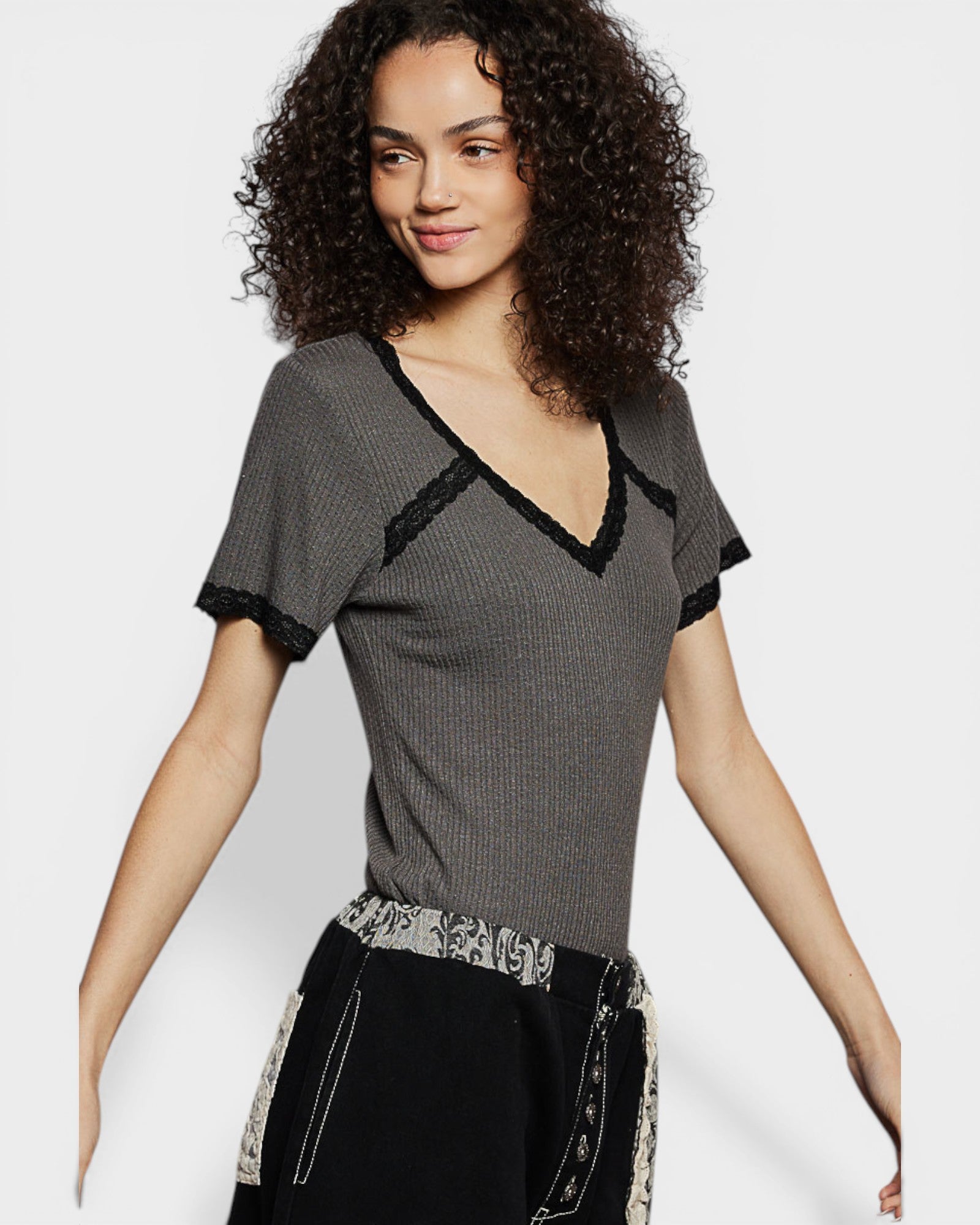 Woman wearing a gray short-sleeve top with lace details on a white background
