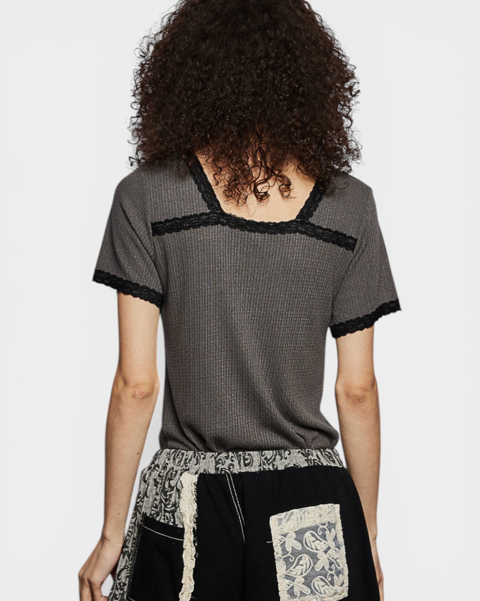 Person wearing a gray textured top with black trim on a white background