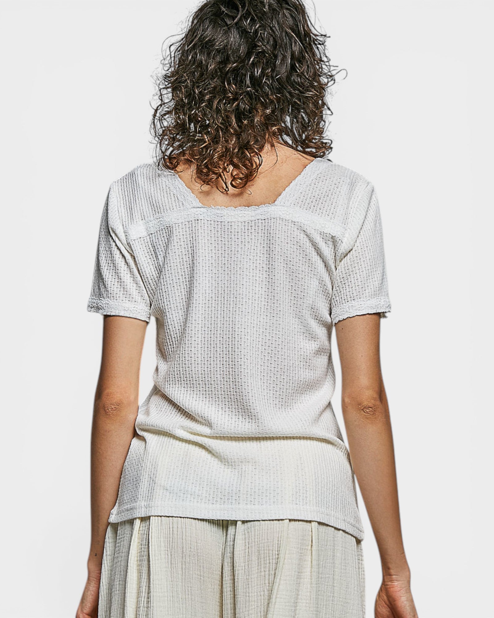 Person wearing a light-colored top and pants on a plain background