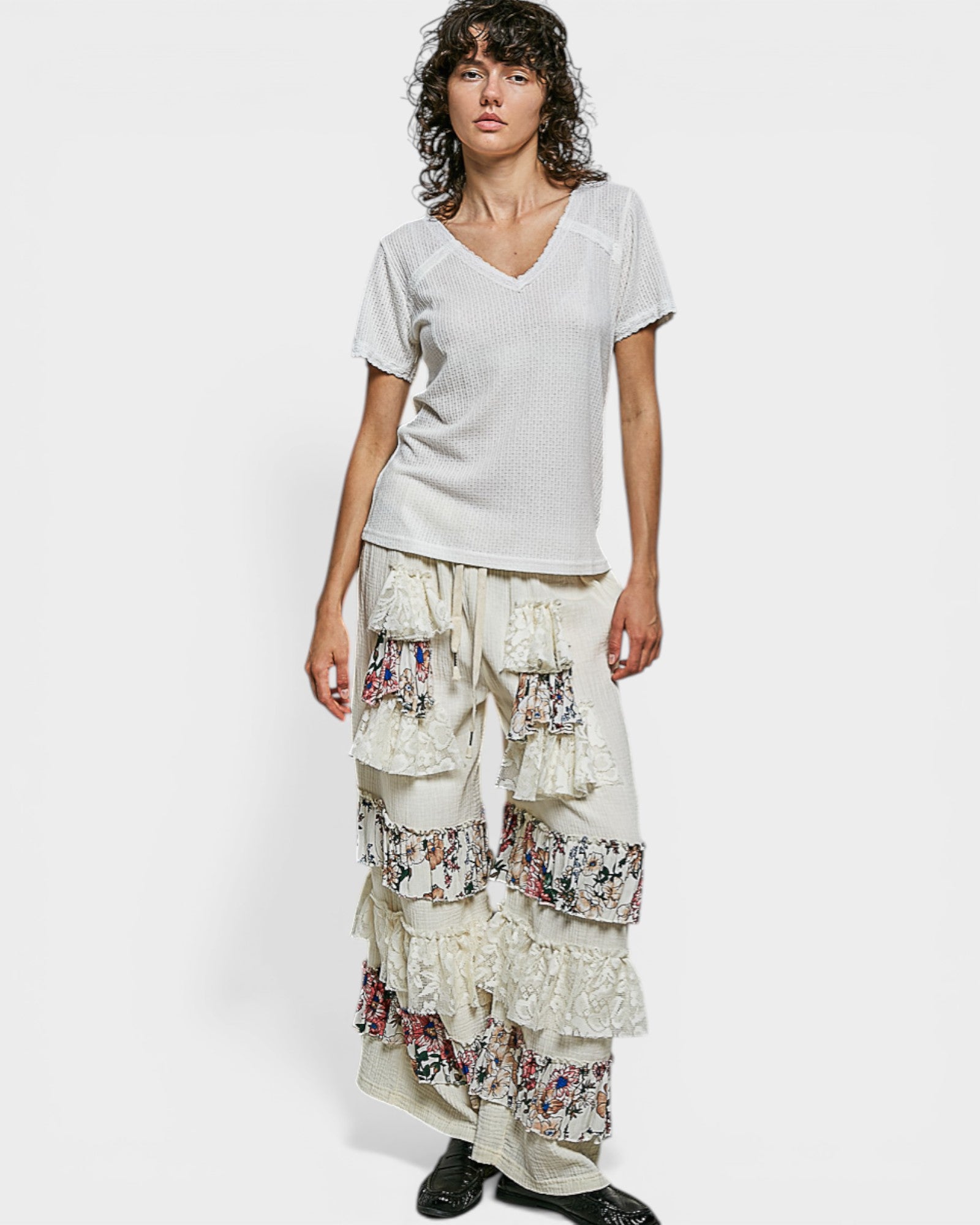 Person wearing a white top and floral layered skirt on a white background