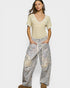 Woman wearing a beige top and patterned pants on a white background