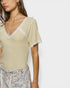 Woman wearing a light-colored top with lace trim on a plain background