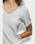White textured short-sleeve top worn by a person on a light gray background