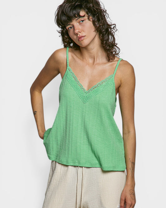 Person wearing a green tank top against a plain background