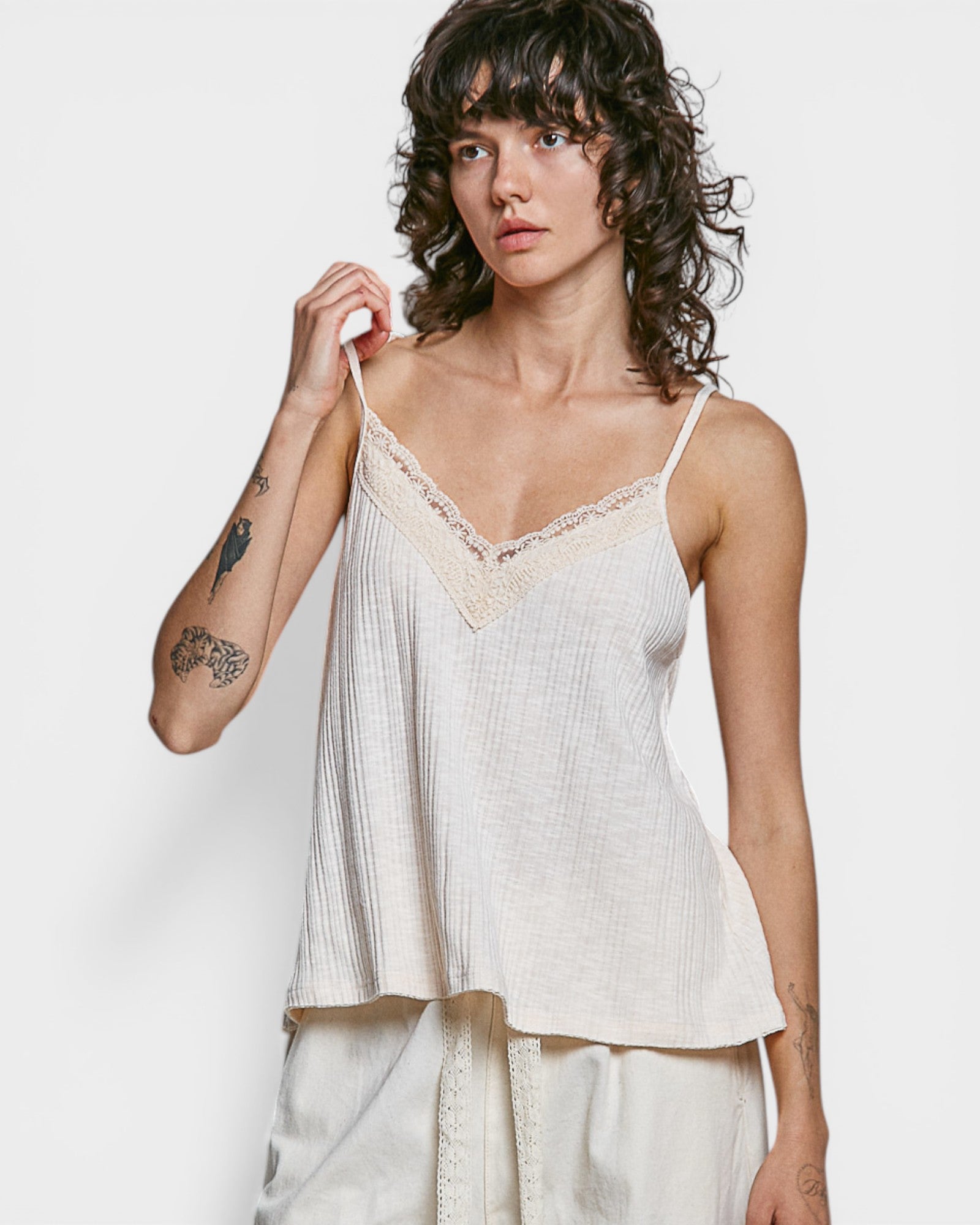 Woman wearing a light-colored lace-trimmed top against a plain background
