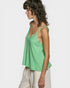 Woman wearing a green sleeveless top with lace details on a white background