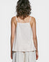 Woman wearing a light-colored sleeveless top and pants on a white background
