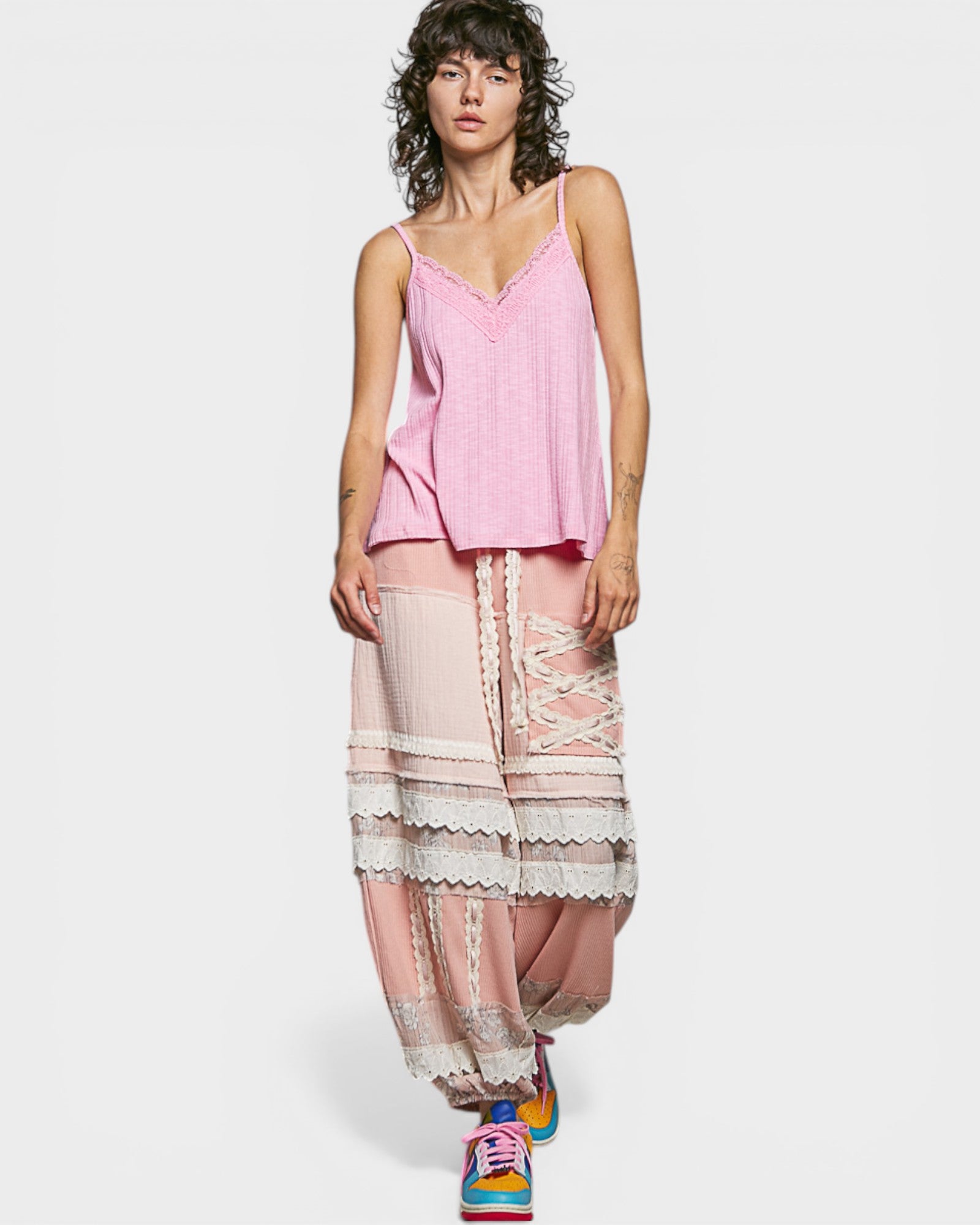 Woman wearing a pink top and patterned pants on a white background