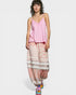 Woman wearing a pink top and patterned pants on a white background