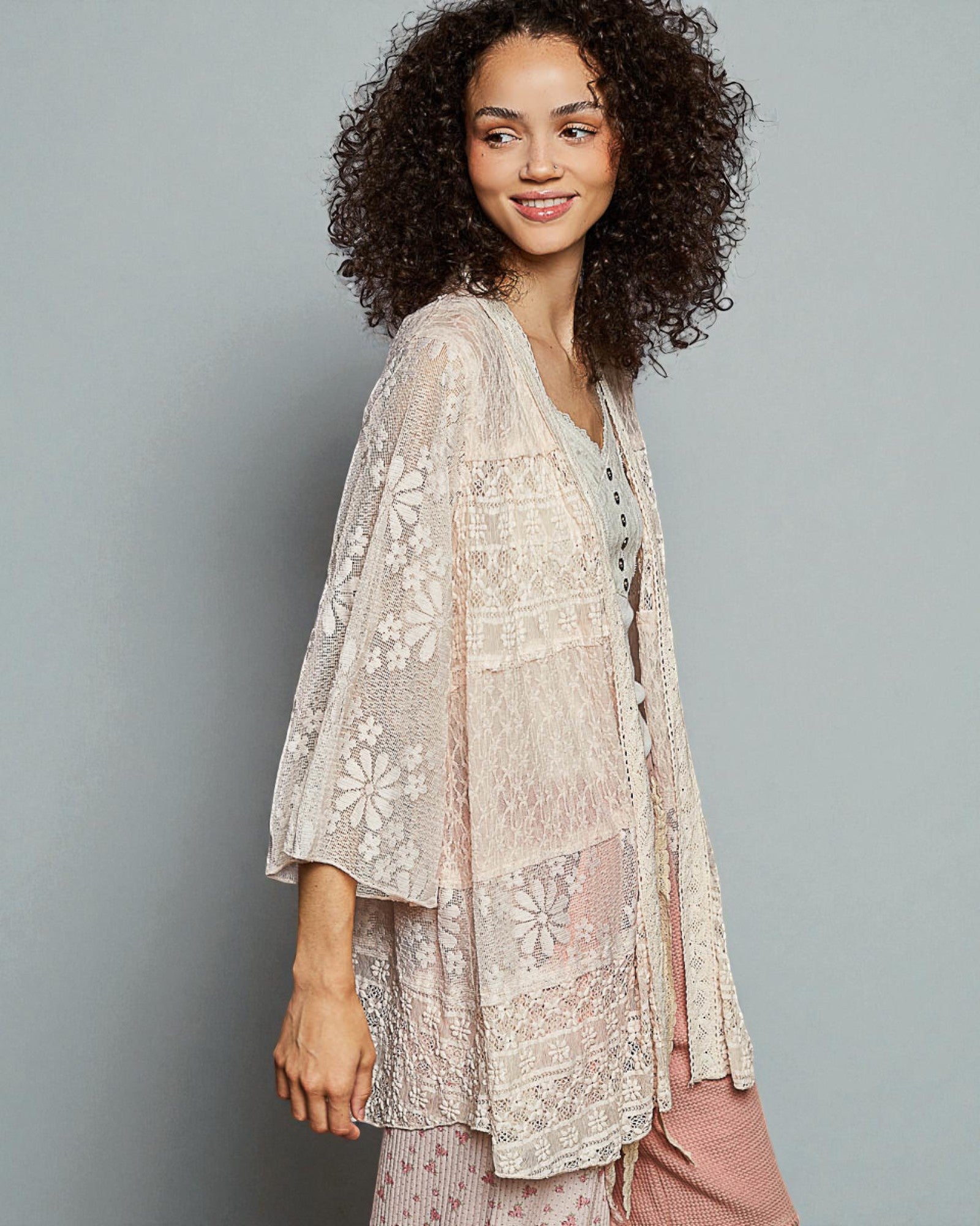 Woman wearing a floral lace kimono over a matching dress against a gray background