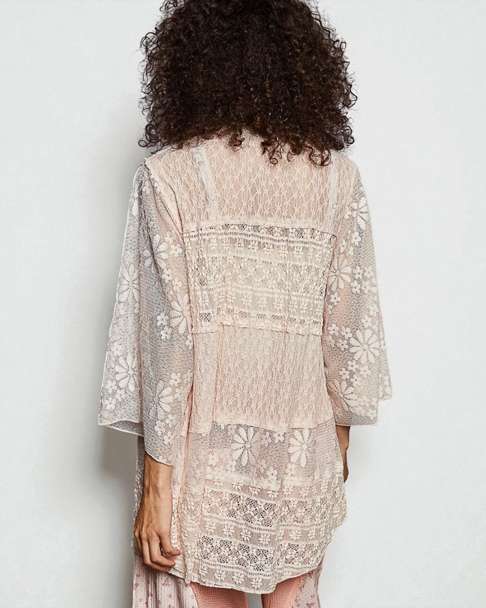 Woman wearing a beige embroidered dress with a plain background