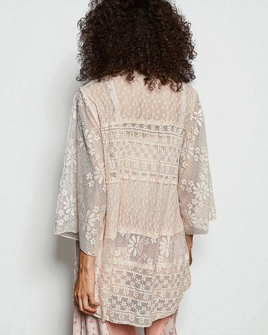 Woman wearing a beige embroidered dress with a plain background