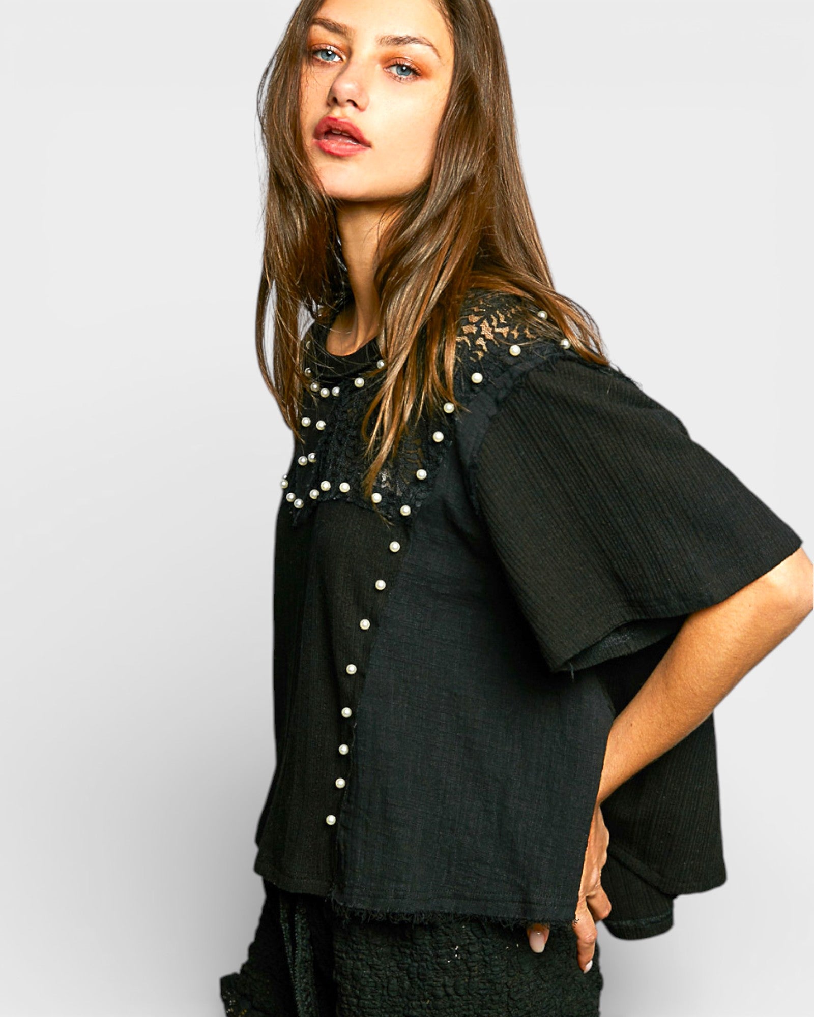 Woman wearing a black outfit with lace details on a white background