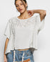 Woman wearing a white lace top and denim shorts on a plain background
