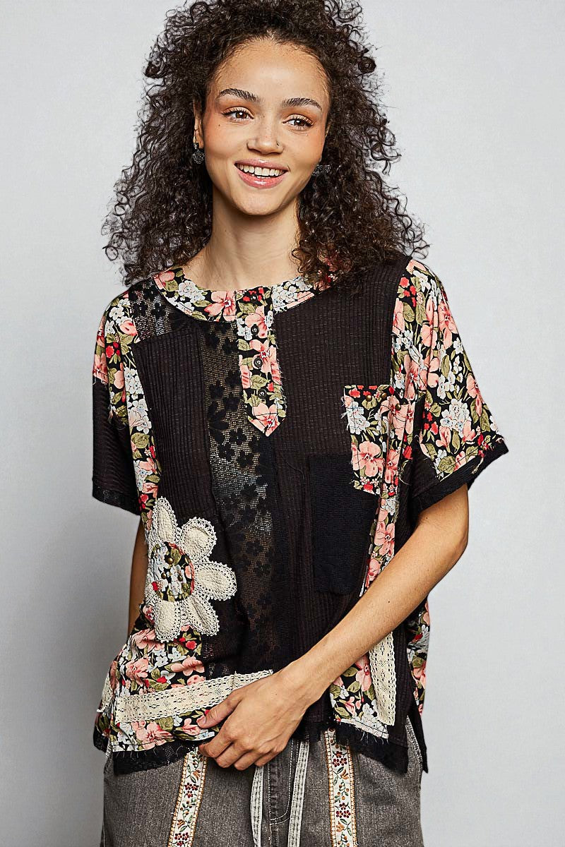 Woman wearing a floral kimono-style jacket over a black top with a white teddy bear design.