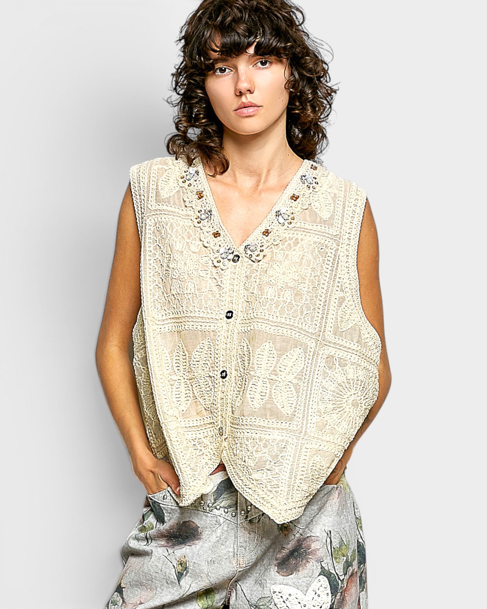 Woman wearing a beige embroidered vest against a white background