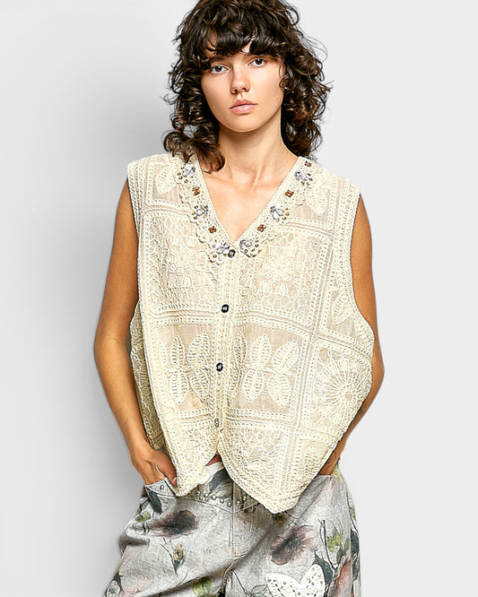 Woman wearing a beige embroidered vest against a white background