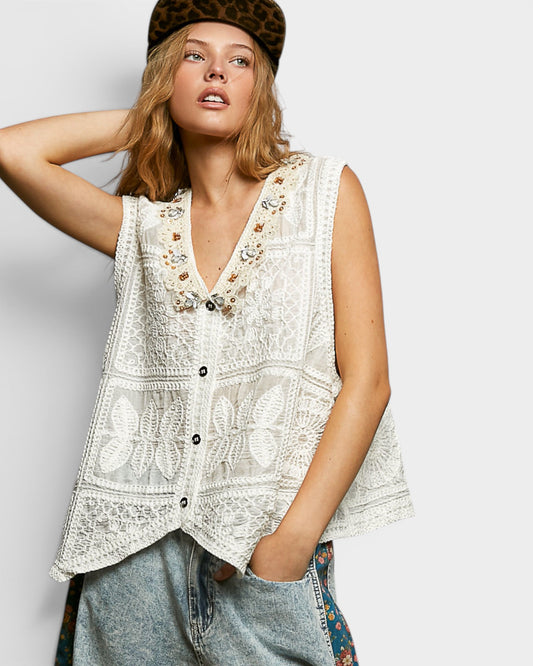 Woman wearing a white lace vest and leopard print hat against a light background