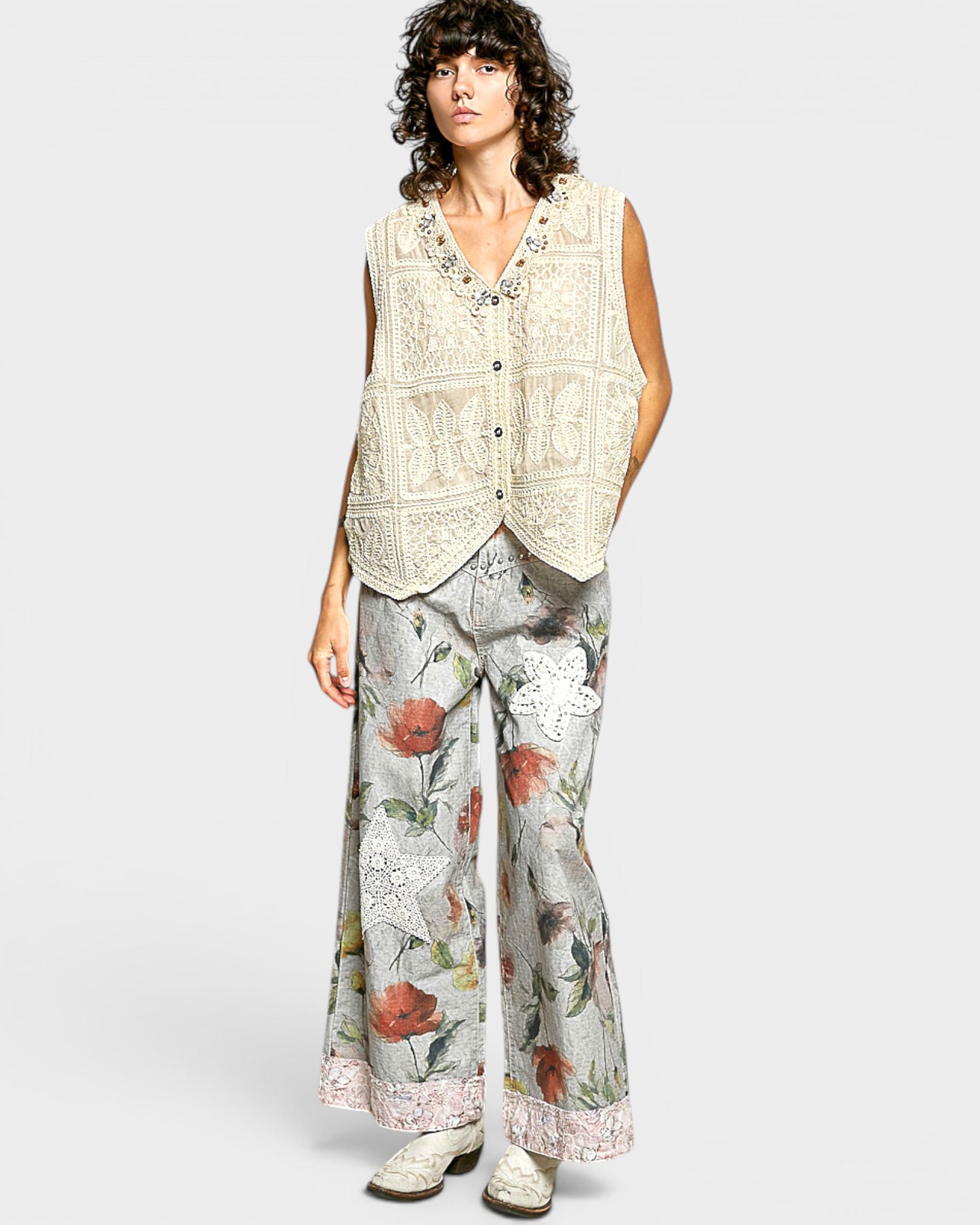 Woman wearing a patterned vest and floral pants on a white background