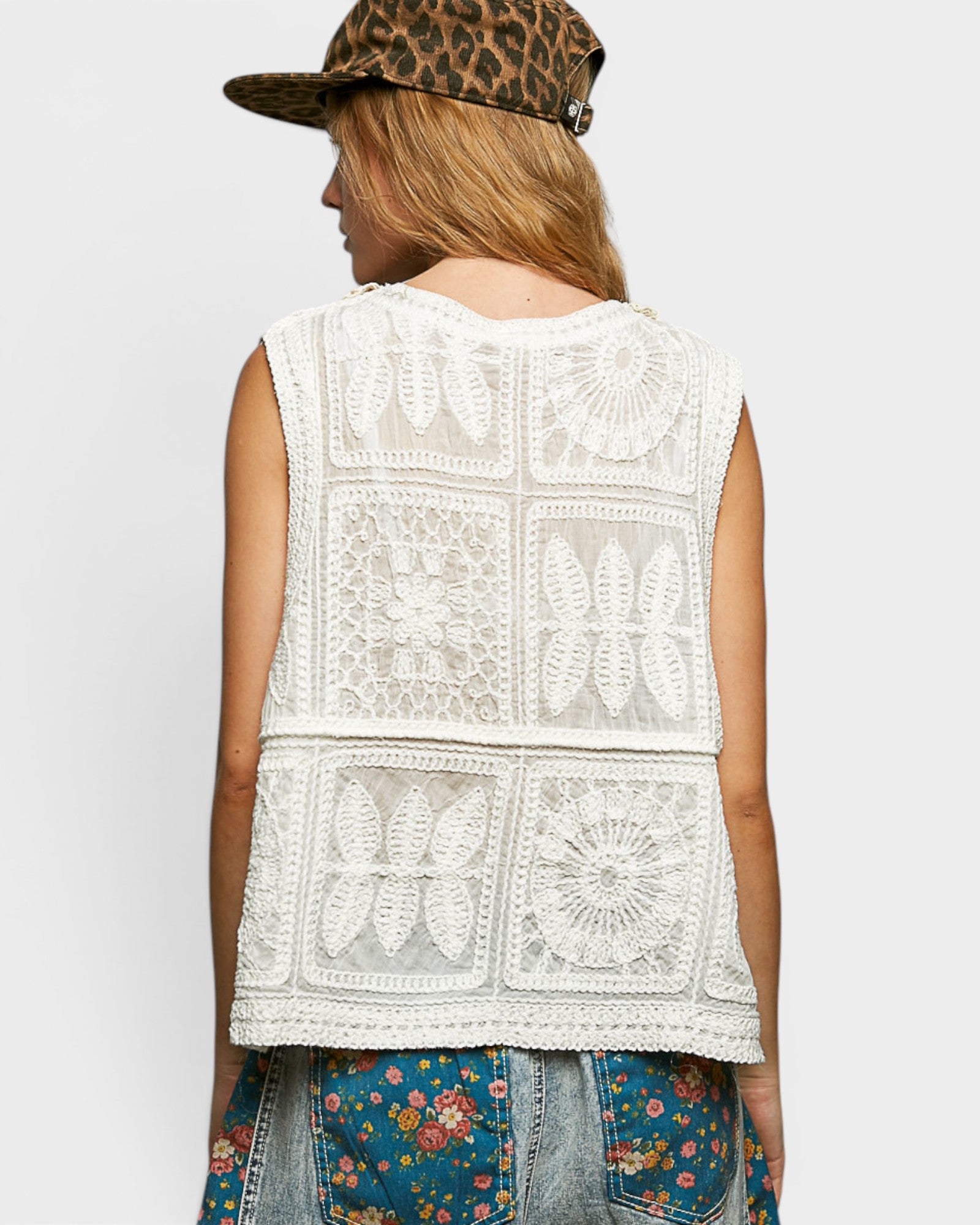 Person wearing a sleeveless crochet top with a white background