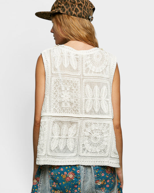 Person wearing a sleeveless crochet top with a white background