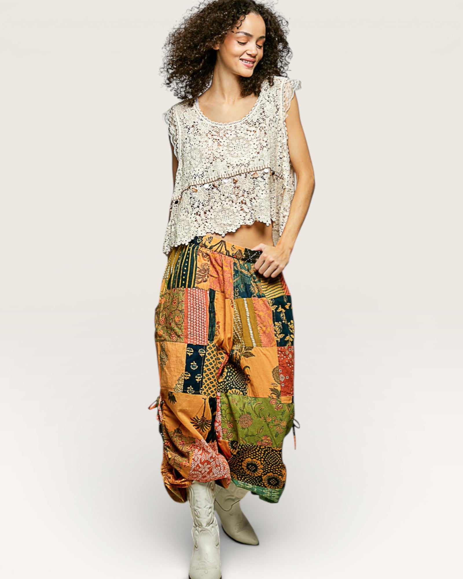 Woman wearing a patterned top and colorful patchwork skirt on a white background