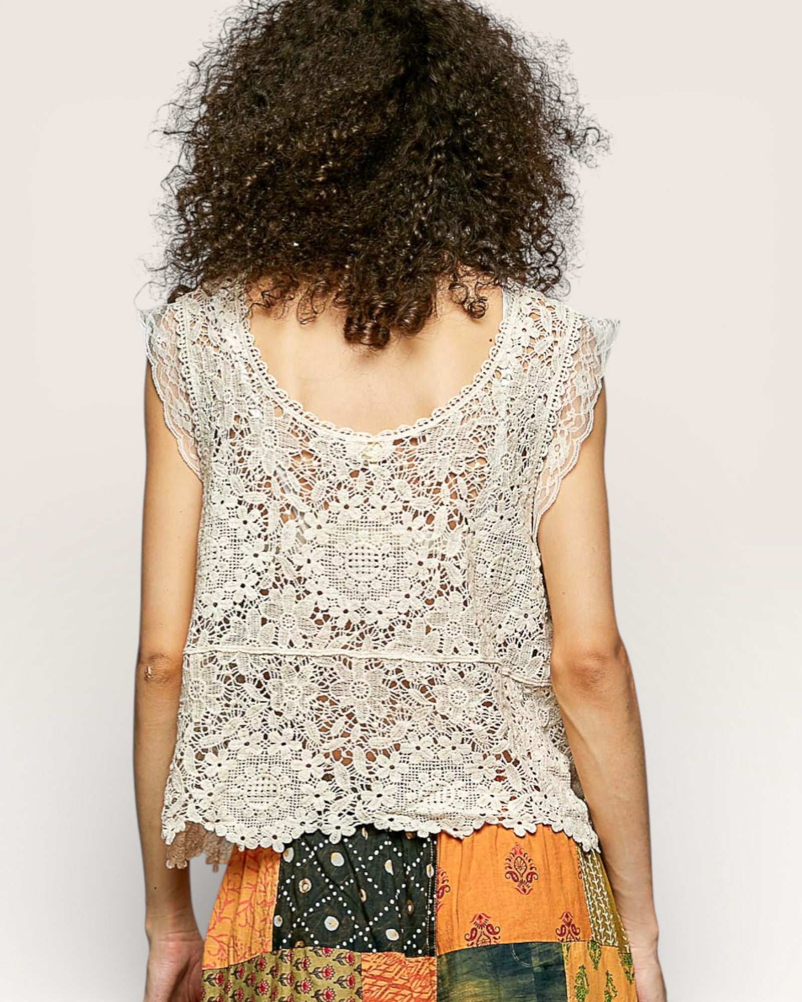 Person wearing a lace top with a neutral background