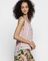 Woman wearing a pink sleeveless top with floral pants on a white background