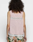 Woman wearing a pink sleeveless top with lace details on a white background