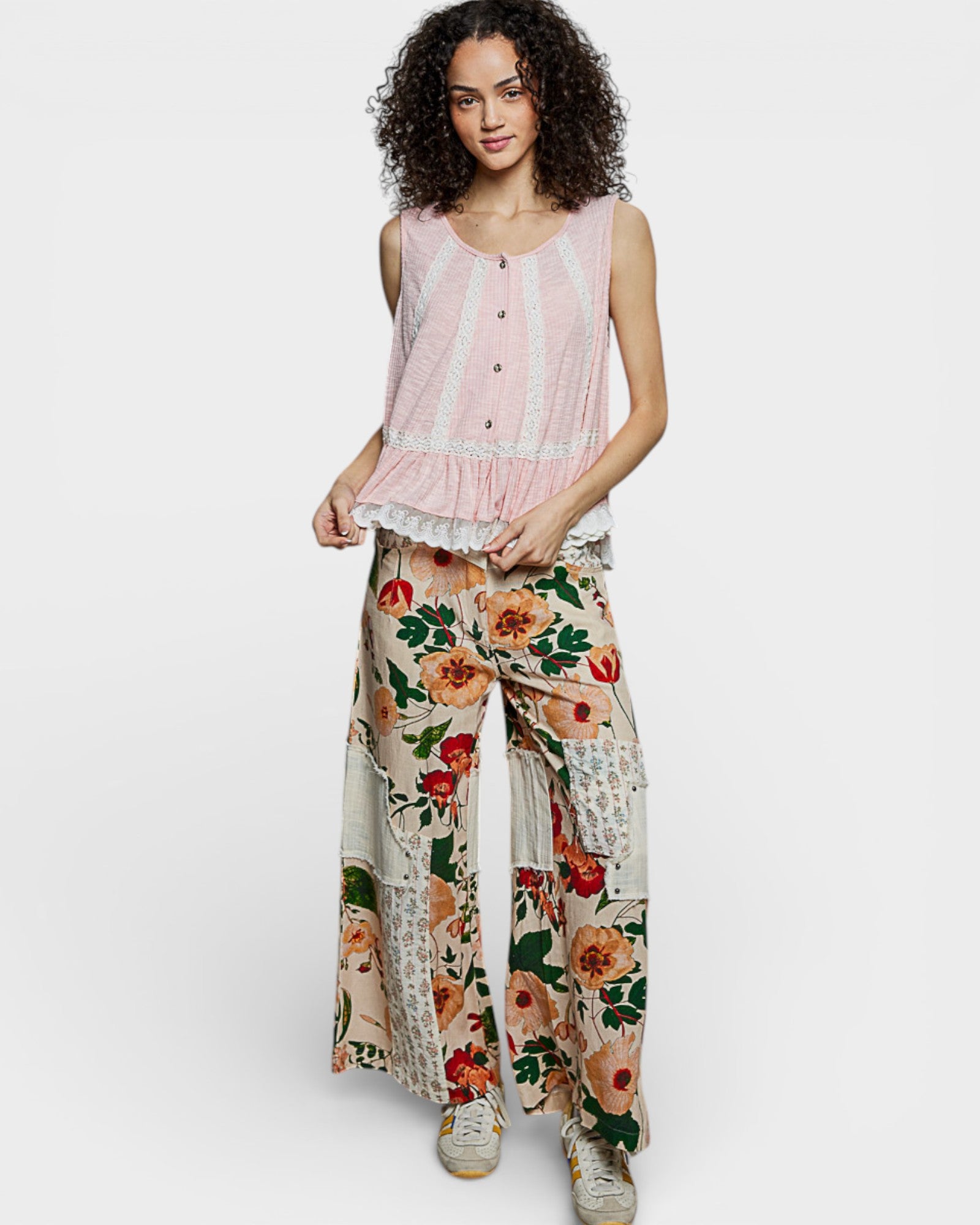 Woman wearing a pink sleeveless top and floral pants on a white background