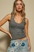 Woman wearing a gray ribbed tank top and floral denim shorts against a beige background