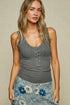 Woman wearing a gray ribbed tank top with a beige background