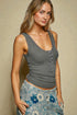 Woman wearing a gray tank top and floral skirt against a beige background