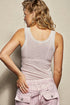 Woman wearing a light pink sleeveless top and pants against a neutral background