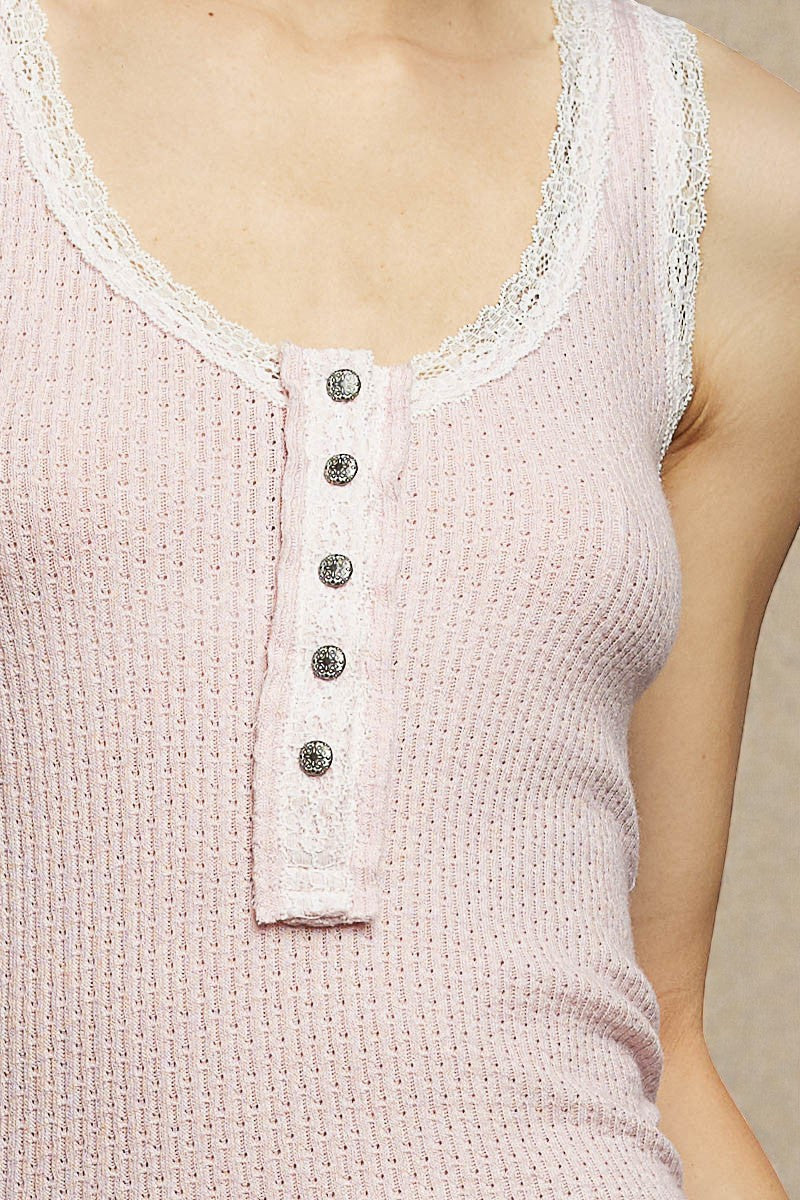 Close-up of a light pink sleeveless top with lace trim and buttons.