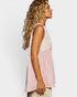 Woman wearing a sleeveless pink and white top against a plain background