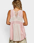 Woman wearing a pink and white sleeveless top with a white background