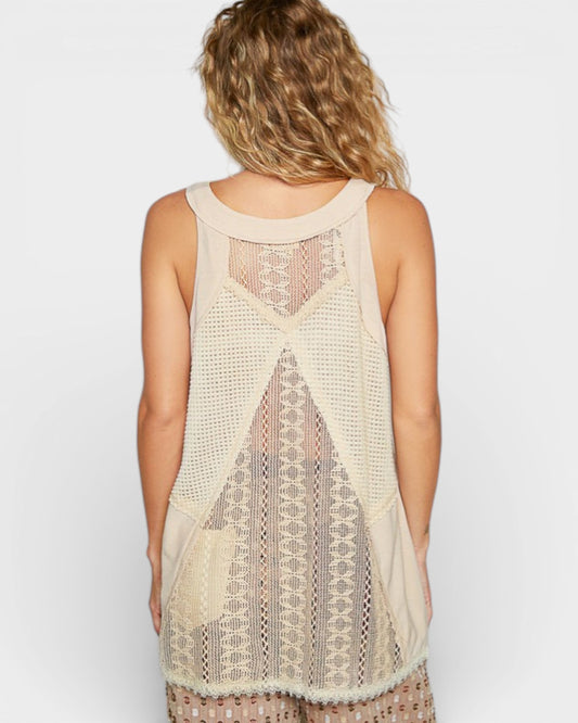 Woman wearing a beige crochet tank top with a plain background