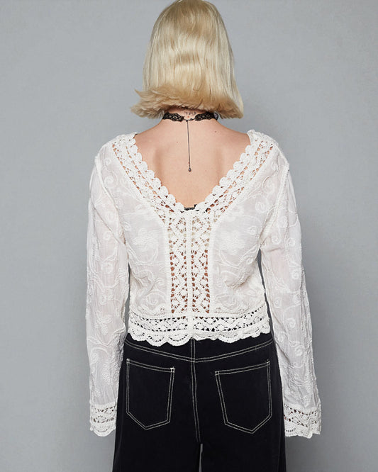 Person wearing a white lace top with a gray background